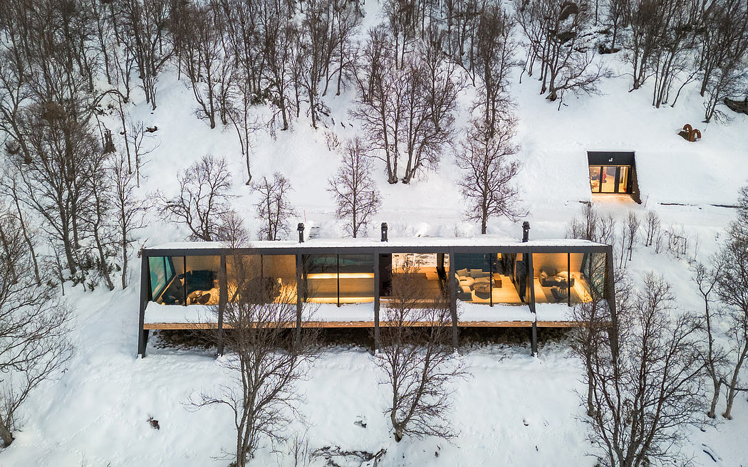 A modern, glass-enclosed cabin nestled in a snowy forest, with warm interior lighting.