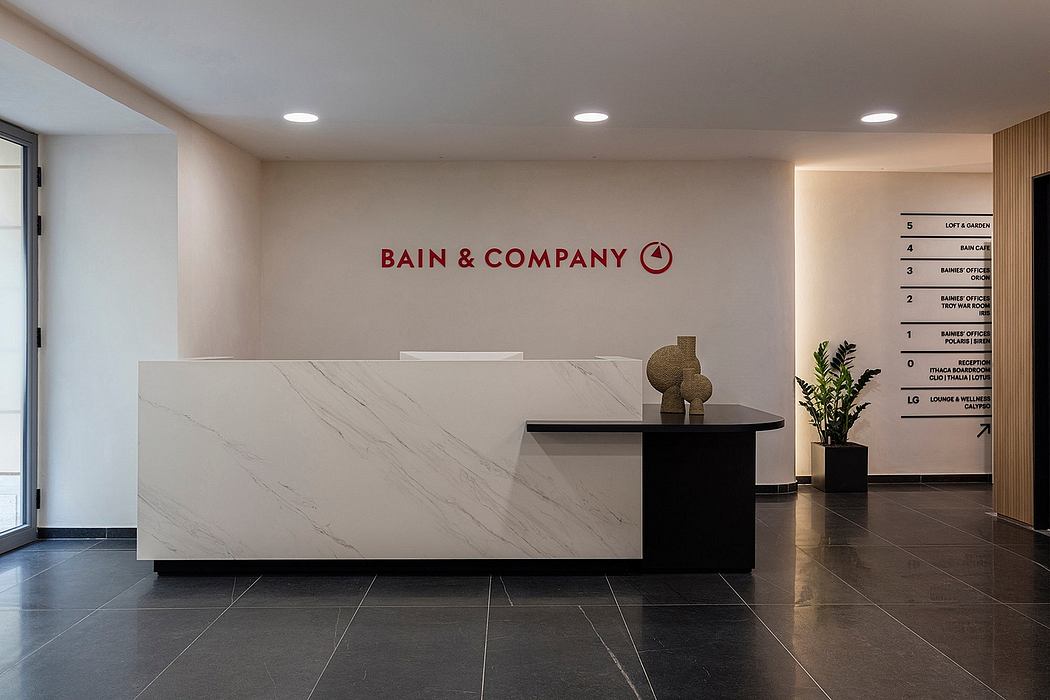 The lobby features a modern reception desk with sleek marble surfaces and minimalist decor.