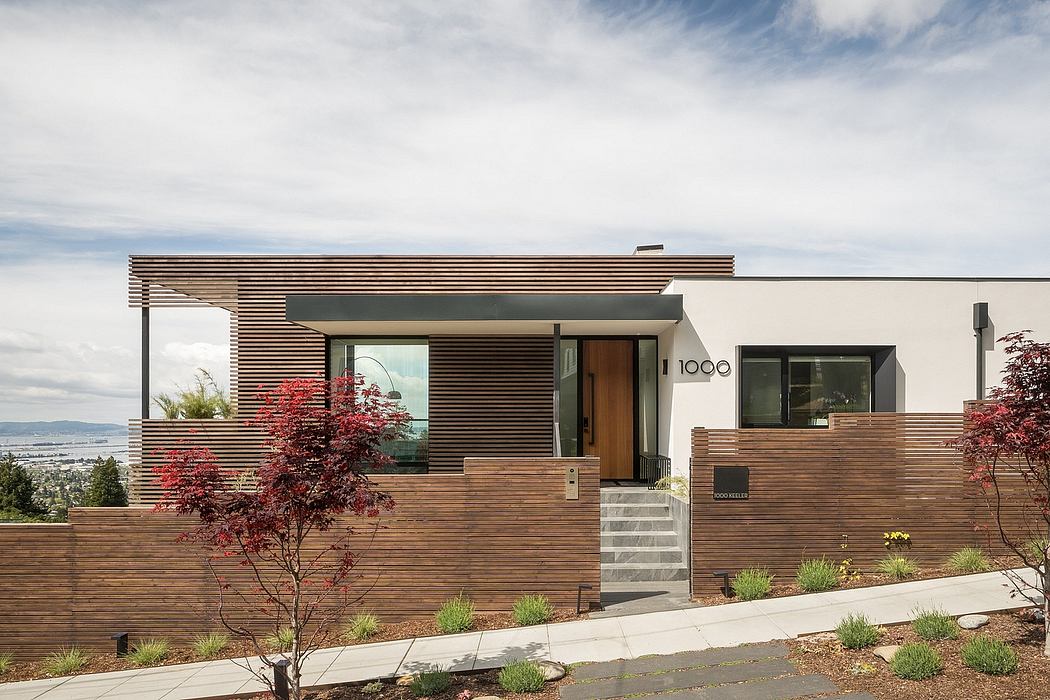 Modern wood-paneled home with expansive windows, landscaped yard, and architectural details.