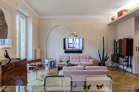 Cozy, mid-century modern living room with plush velvet sofa, arched lamp, and wooden furniture.