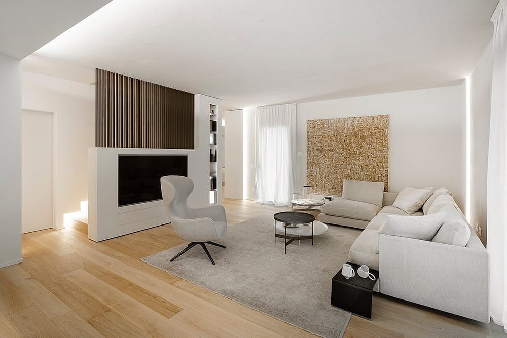 Minimalist living room with white sofas, wooden floors, and a unique textured wall feature.