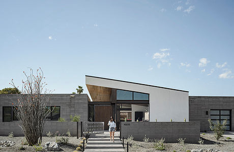 Modern, minimalist building with clean lines, stone and wood facade, and landscaping.