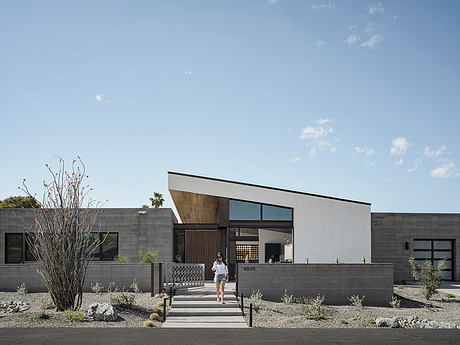 Modern, minimalist building with clean lines, stone and wood facade, and landscaping.