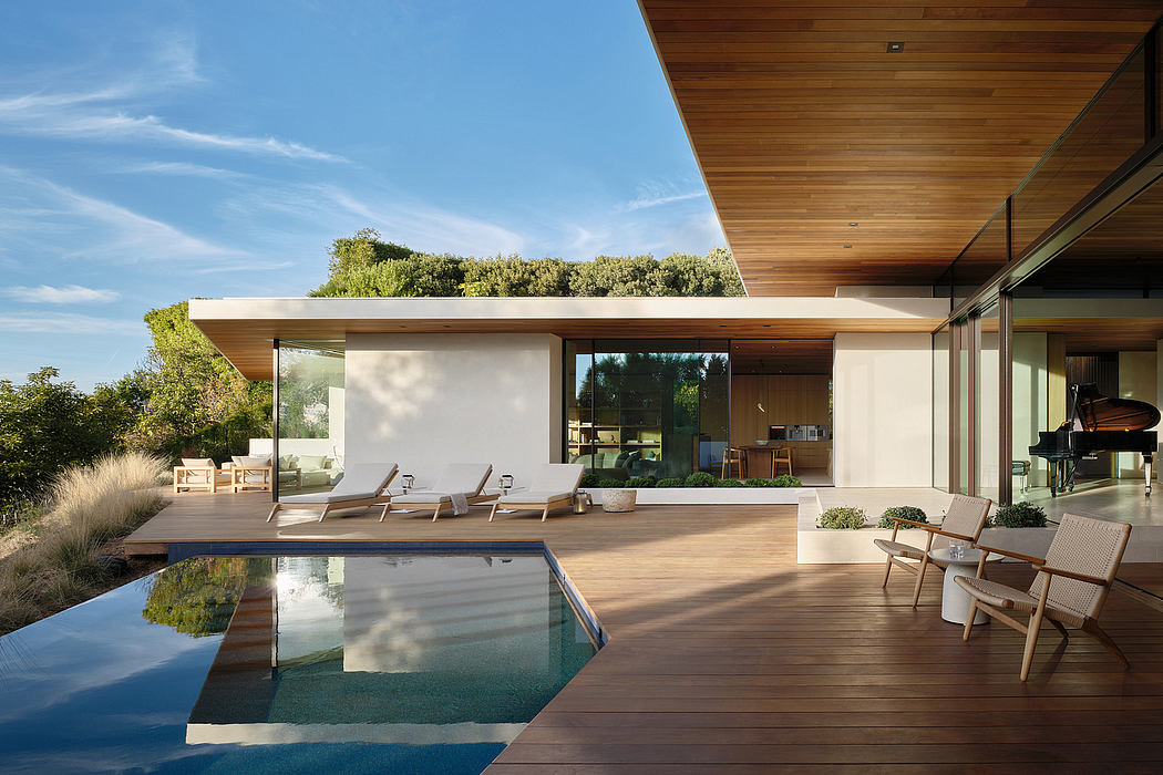A modern home with an expansive deck, infinity pool, and sleek wooden interiors.
