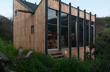 A modern, wood-paneled building with large windows overlooking a natural landscape.