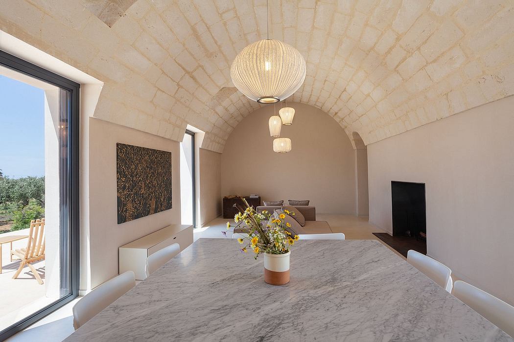 Elegant vaulted ceiling, sleek marble table, and modern lighting fixtures in this cozy space.