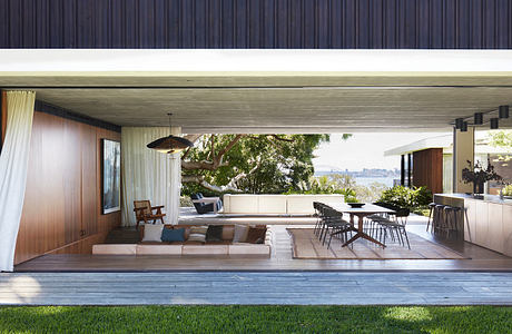 Expansive indoor-outdoor living space with sleek wooden finishes and scenic water views.