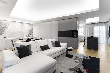 Spacious modern apartment with sleek black and white decor, built-in furniture, and large windows.