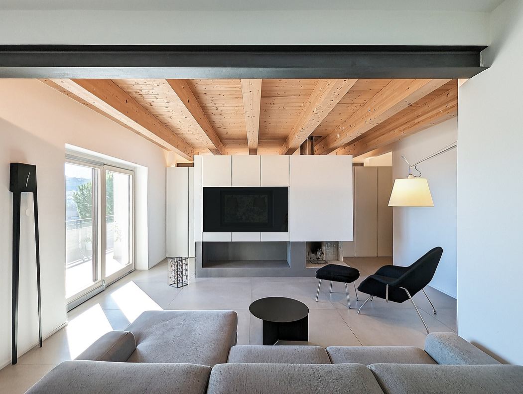 Minimalist living room with exposed wooden beams, built-in storage, and large windows.