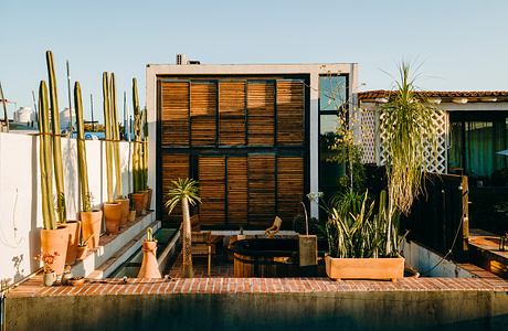 A cozy outdoor living space with wooden screens, potted plants, and a relaxing atmosphere.