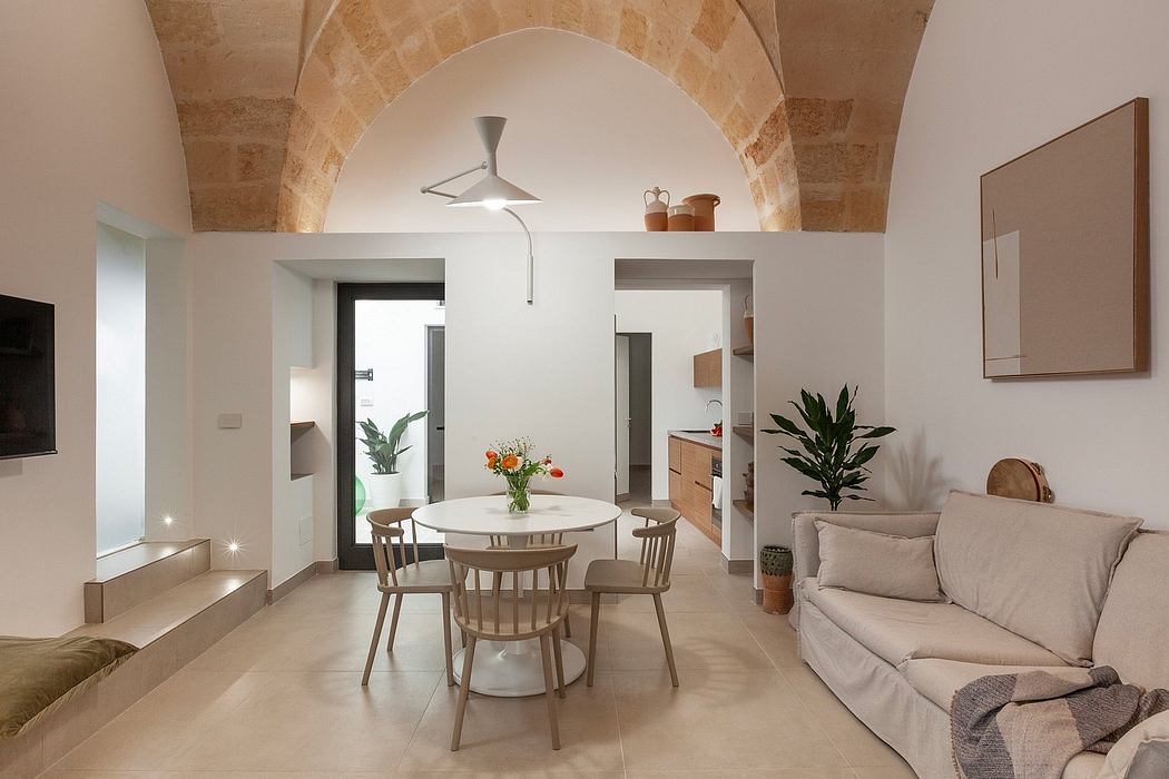 Elegant modern kitchen and dining area with arched stone walls and contemporary furnishings.