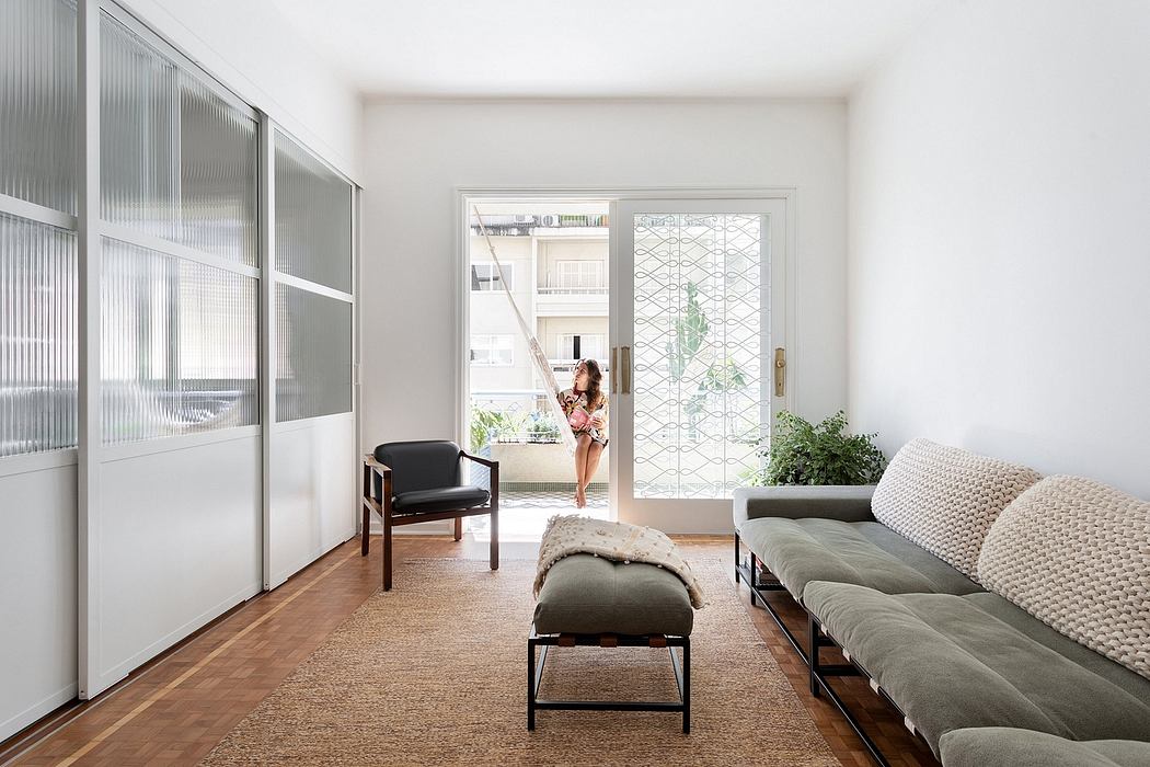 Minimal, open-concept living space with sliding glass panels, plush seating, and plant decor.