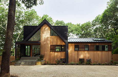 A modern, rustic cabin with a combination of wood, metal, and glass elements.