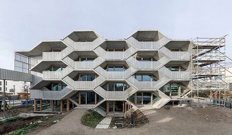 A modern, hexagonal building with an intricate metal exterior and numerous windows.