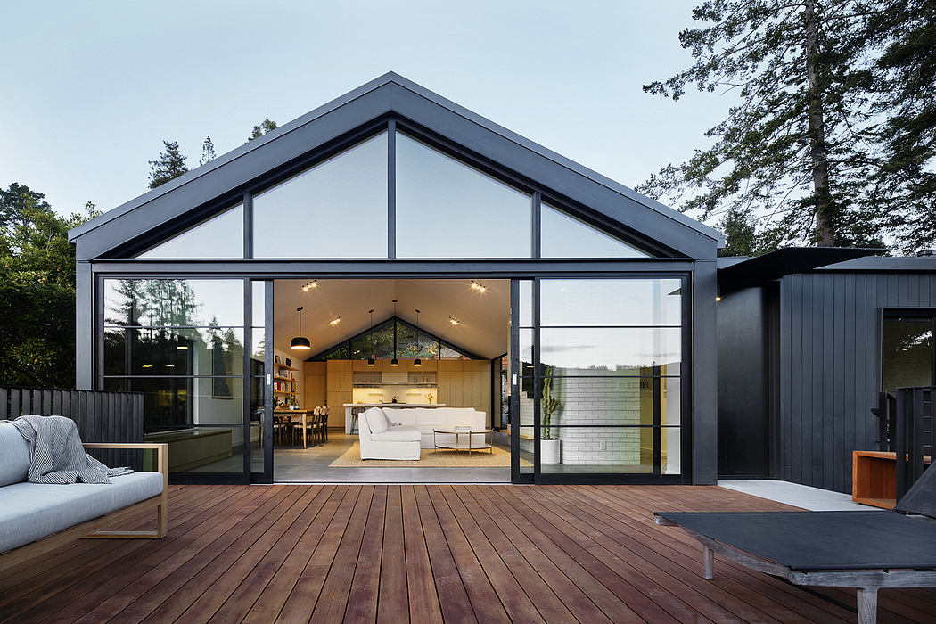 Contemporary glass-walled home with open-concept living space, wood deck, and modern furnishings.