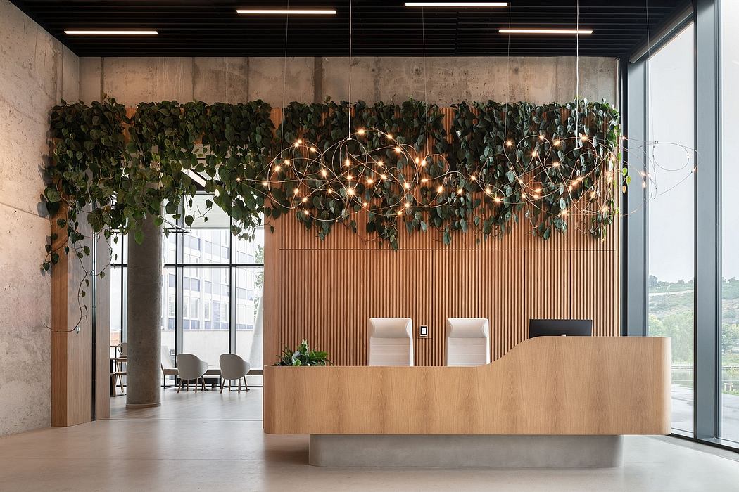 Modern office lobby with lush green foliage, geometric lighting, and wooden furnishings.