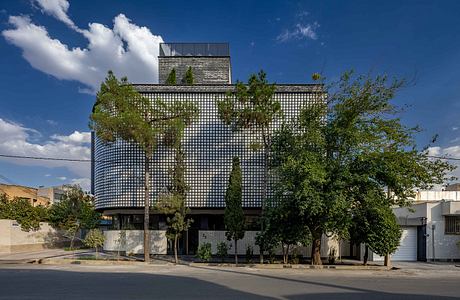 Striking modern building with a facade of gridded glass panels and lush greenery.