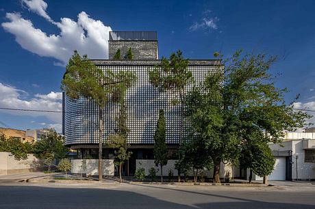 Striking modern building with a facade of gridded glass panels and lush greenery.