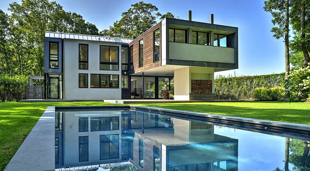 A modern, two-story home with clean lines, large windows, and a reflection pool in the foreground.