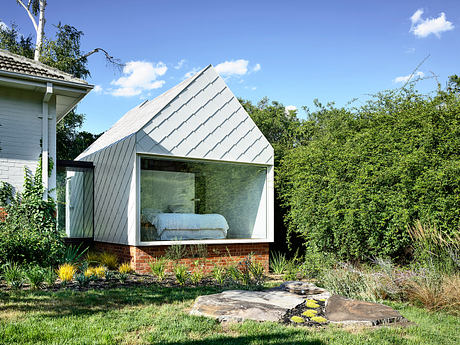 Sleek, geometric architecture with large glass walls and brick base, surrounded by lush greenery.