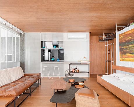 A warm, modern open-plan living space featuring wood, glass, and metal finishes.