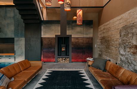 Cozy living room with stone fireplace, leather sofas, patterned rug, and hanging lamps.