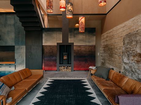 Cozy living room with stone fireplace, leather sofas, patterned rug, and hanging lamps.