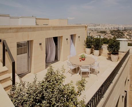 Spacious rooftop terrace with a dining table and plants overlooking the city skyline.