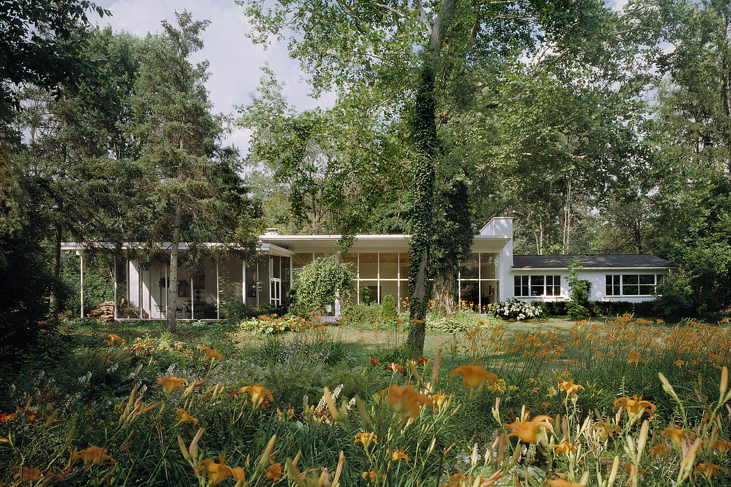 A mid-century modern home surrounded by lush greenery and vibrant flowers.