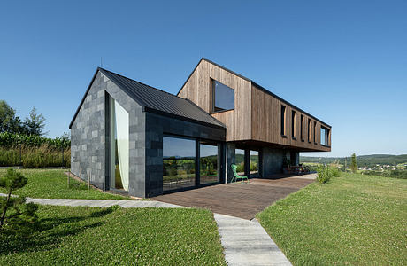 Striking modern architecture with contrasting materials and large windows overlooking lush greenery.