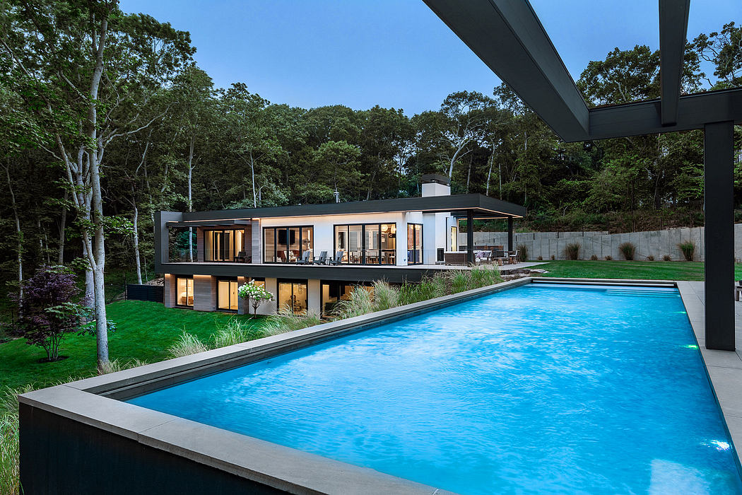 Sleek modern house with pool, surrounded by lush greenery and a serene natural setting.
