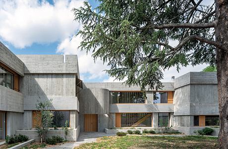 A modernist concrete residential complex with wood accents and lush surrounding greenery.