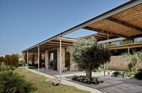 A modern architectural structure with bamboo and glass elements, surrounded by lush vegetation.