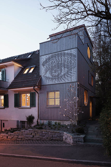 A striking modern residential building with a unique perforated facade and warm interior lighting.