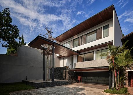 Contemporary two-story home with sleek, angular design, stone walls, and large windows.