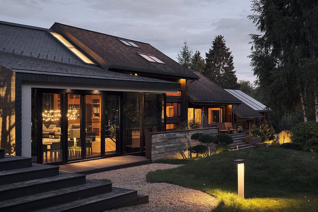 A modern rustic house with expansive windows, a covered patio, and well-lit interiors.