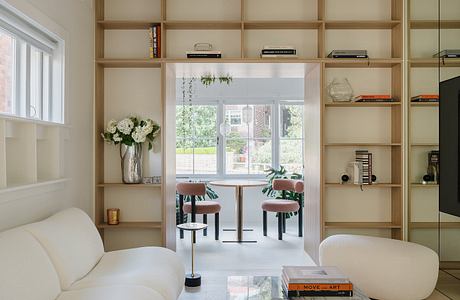 Spacious room with built-in wooden shelves, white sofa, and dining area with chairs.