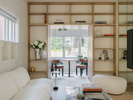 Spacious room with built-in wooden shelves, white sofa, and dining area with chairs.