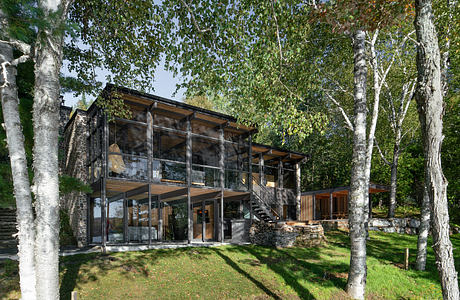 Striking modern glass and wood cabin nestled in lush forest, with sleek architectural design.