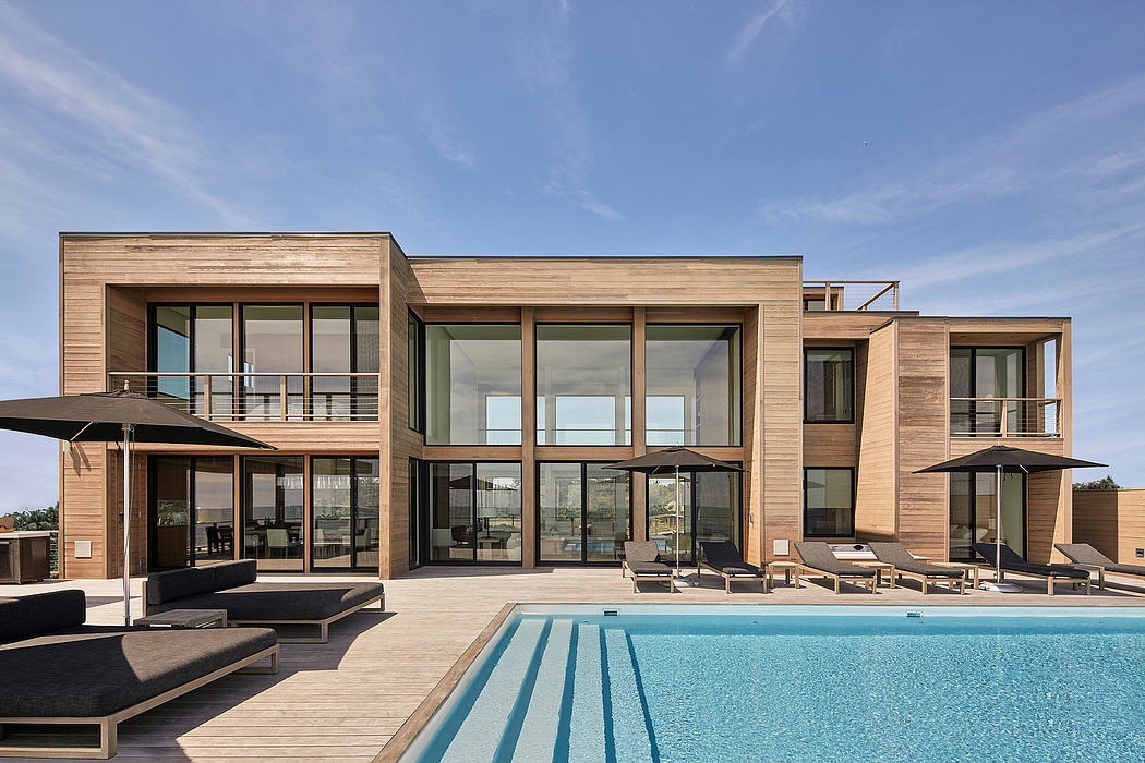 Sleek, modern architecture featuring extensive glass panels, wood siding, and an inviting pool.