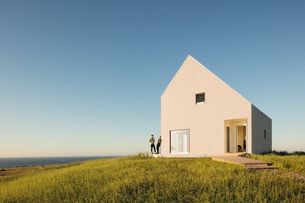 A modern, minimalist house with a striking triangular roof and large windows overlooking the landscape.