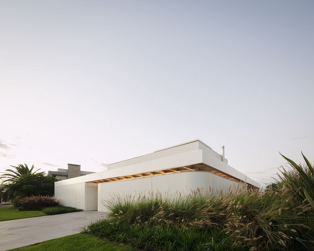 A modern, low-profile structure with a wooden canopy and lush surrounding vegetation.