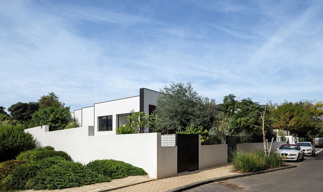 Modern house with minimalist design, white walls, and lush landscaping surrounding the property.