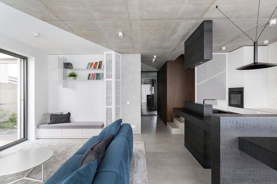 Minimalist open-concept living space with concrete ceiling, sleek black kitchen, and built-in seating.