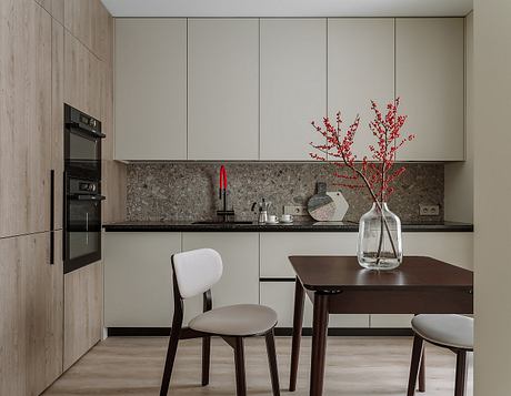 Minimalist kitchen with wooden cabinets, granite countertop, and decorative red branches.