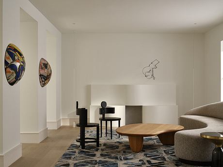 Elegant modern living space with abstract artworks, wooden furniture, and patterned rug.