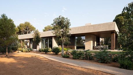 A modern, single-story home with large windows, a covered porch, and lush landscaping.