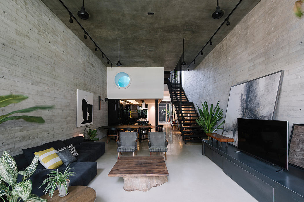 Spacious industrial-style living room with concrete walls, modern furniture, and hanging light fixtures.