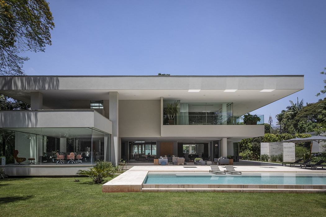 Sleek modern home with open-concept design, pool, and lush greenery surrounding.