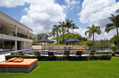 Serene outdoor lounge area with palm trees, umbrellas, and a sleek modern pool.